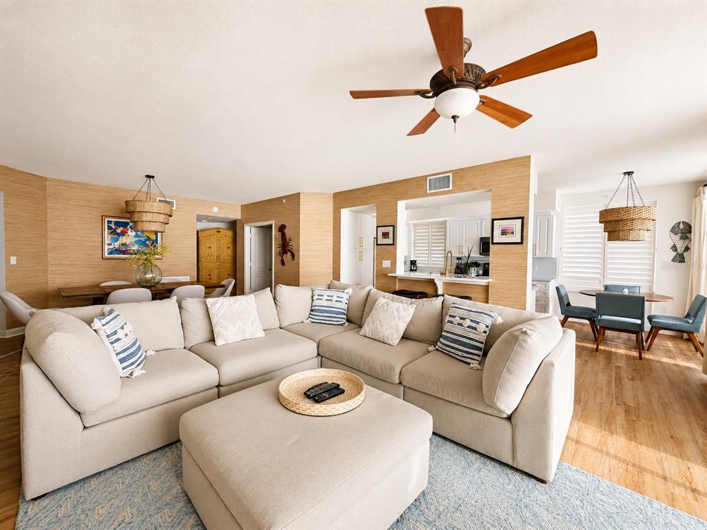 A living room with a large sectional sofa, wood-paneled walls, and an open kitchen — 10 PAPAYA STREET UNIT 901, CLEARWATER BEACH, FL