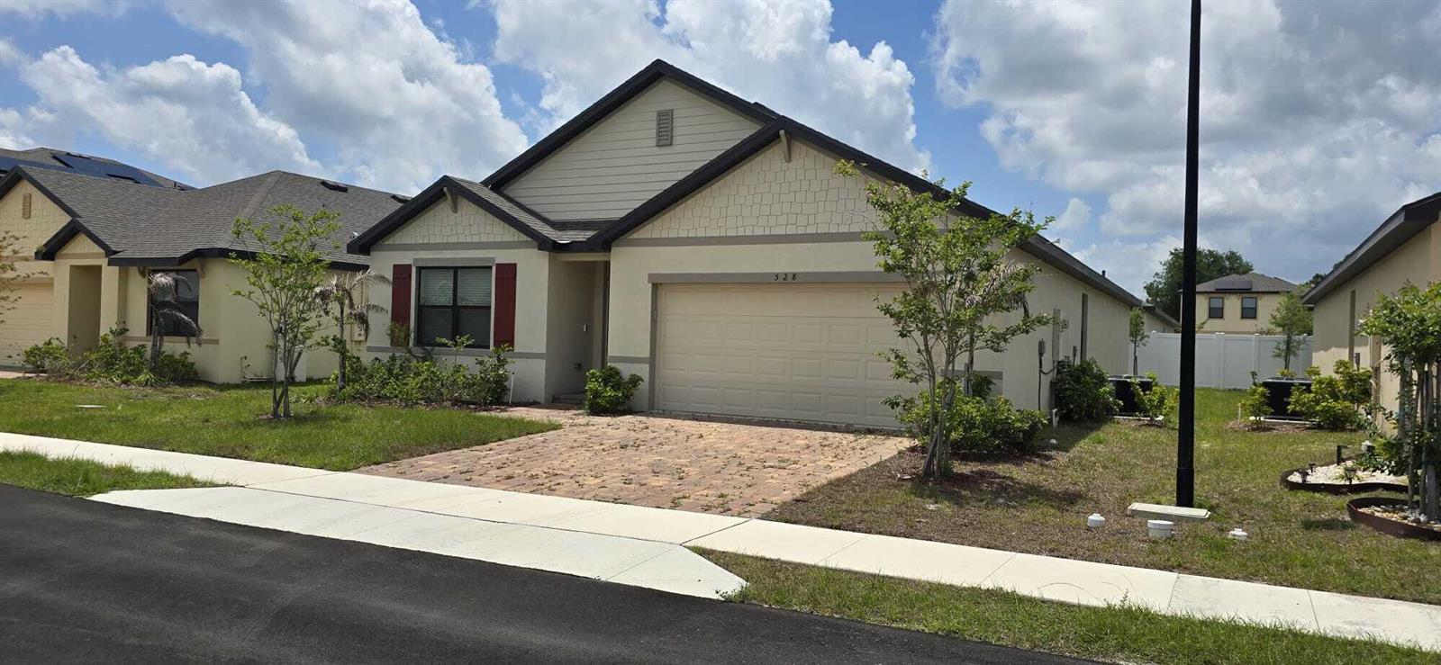 A one-story suburban house with a beige stucco exterior, a two-car garage, and a paver driveway — 528 Seafoam Circle, Fort Pierce FL 34945, FORT PIERCE, FL