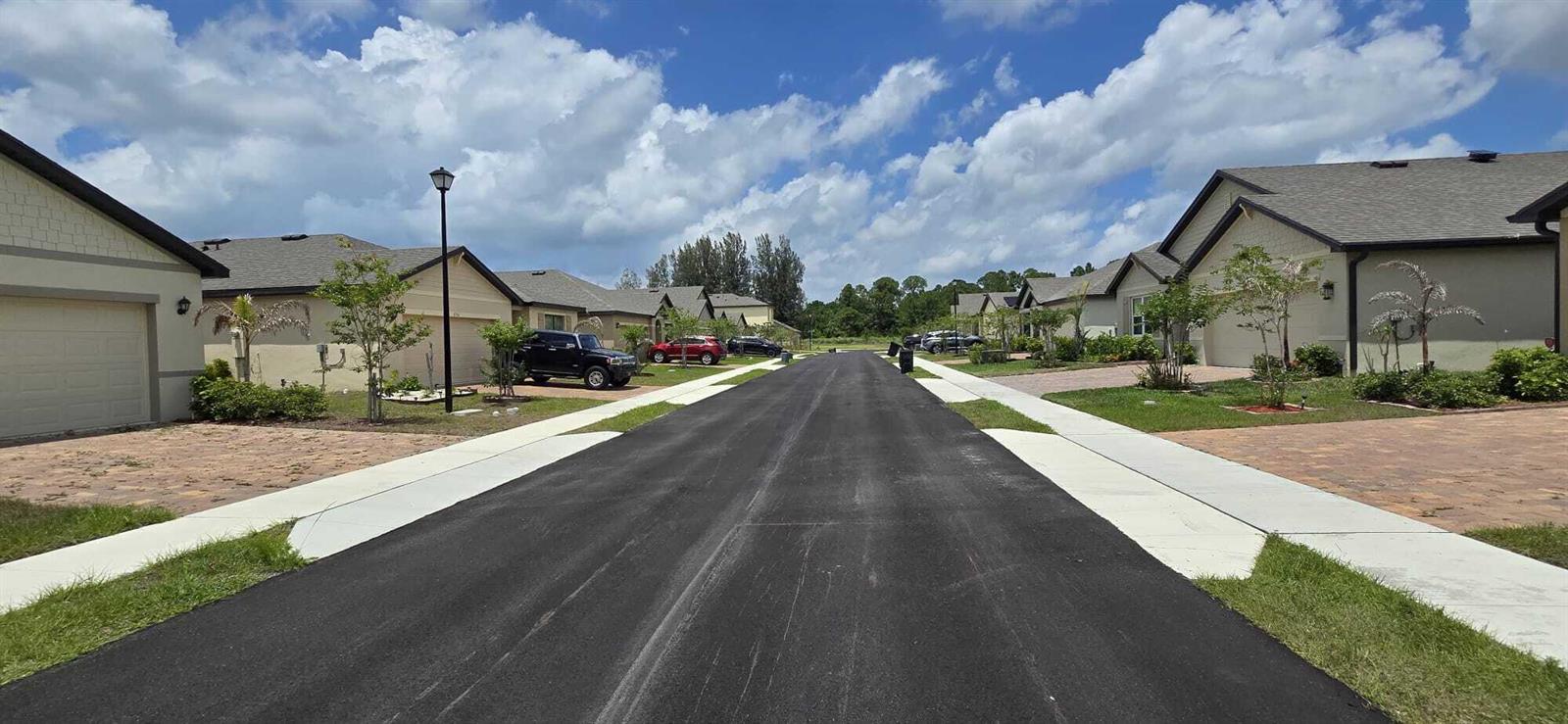 A paved residential street lined with single-story houses and manicured lawns under a cloudy sky — 528 Seafoam Circle, Fort Pierce FL 34945, FORT PIERCE, FL