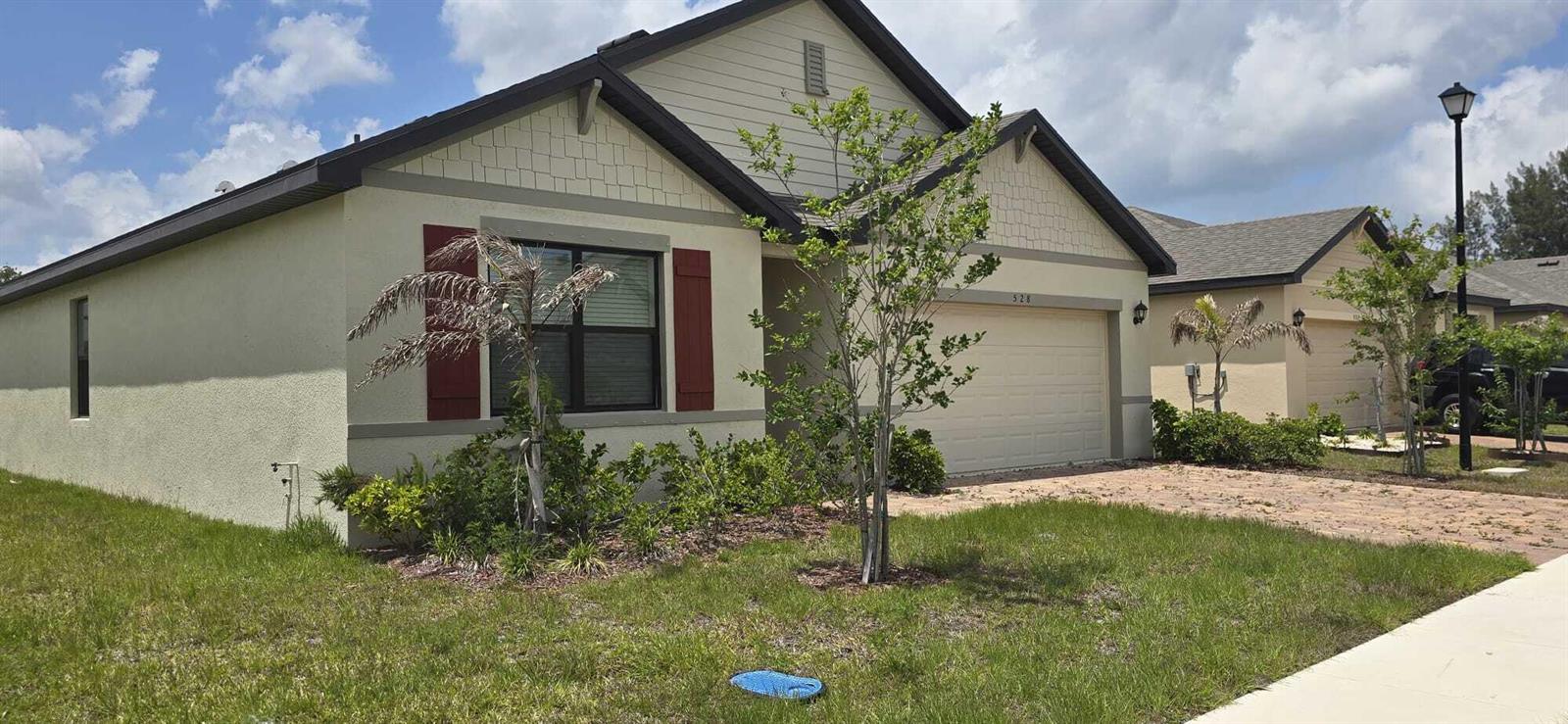 A single-story suburban house with a beige stucco exterior, red shutters, and a two-car garage — 528 Seafoam Circle, Fort Pierce FL 34945, FORT PIERCE, FL