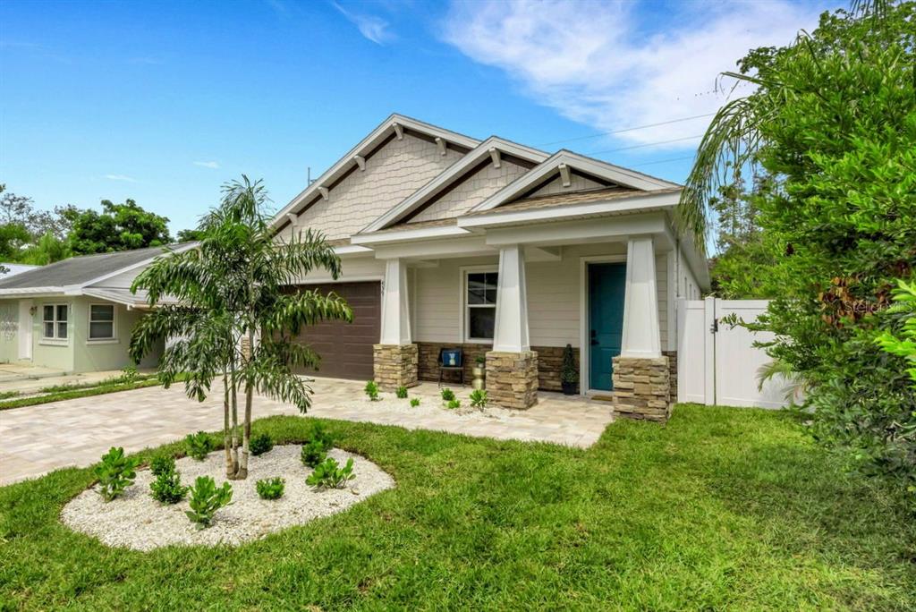 A single-story house with a stone-accented porch, a brown garage door, and a landscaped yard — 439 LOUDEN AVENUE, DUNEDIN, FL
