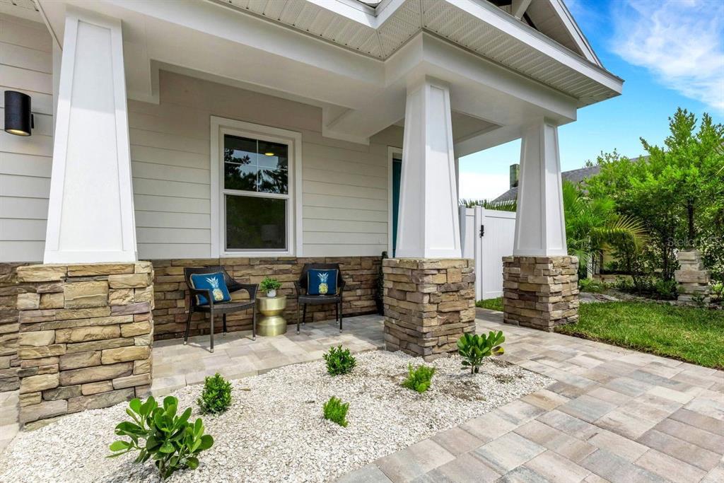 A covered front porch features stone-based columns, two chairs, and a small gravel garden bed — 439 LOUDEN AVENUE, DUNEDIN, FL