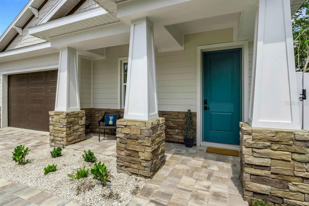 The exterior of a house features a teal front door, stone pillars, and paver walkway — 439 LOUDEN AVENUE, DUNEDIN, FL