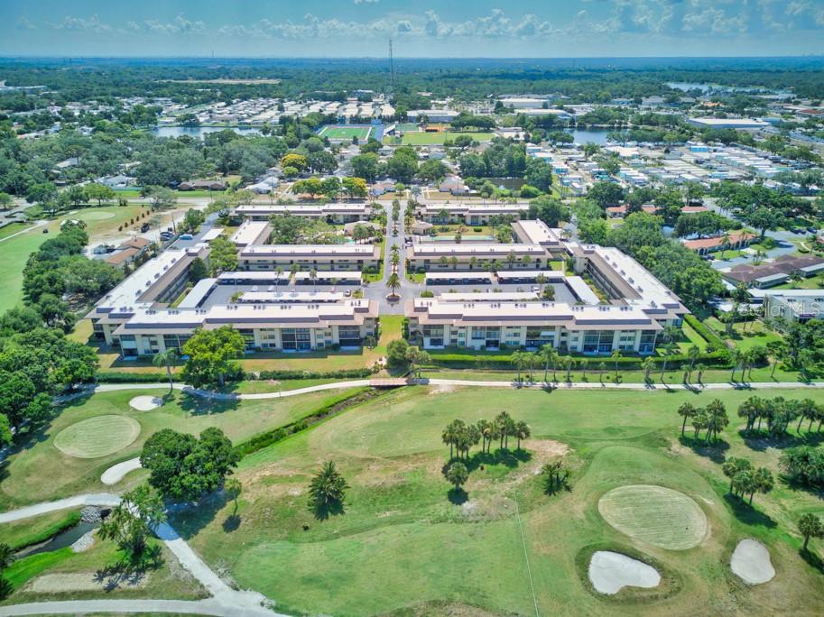 An aerial view shows a multi-story apartment complex situated adjacent to a golf course — 12300 VONN ROAD UNIT 4307, LARGO, FL