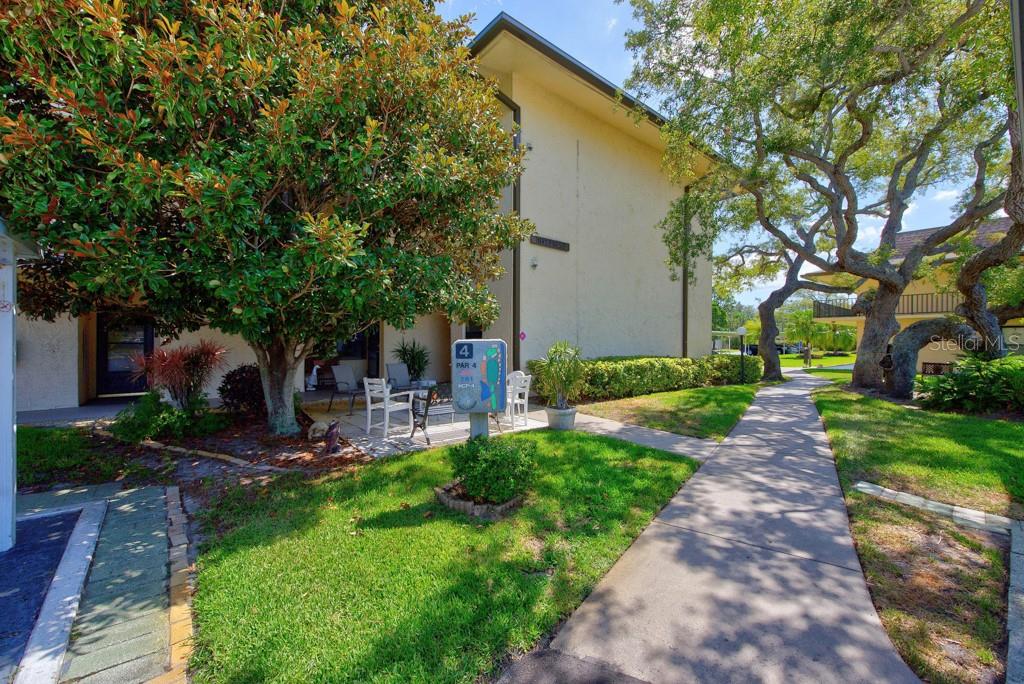 A paved walkway leads past a multi-story building with a patio and golf course signage — 12300 VONN ROAD UNIT 4307, LARGO, FL