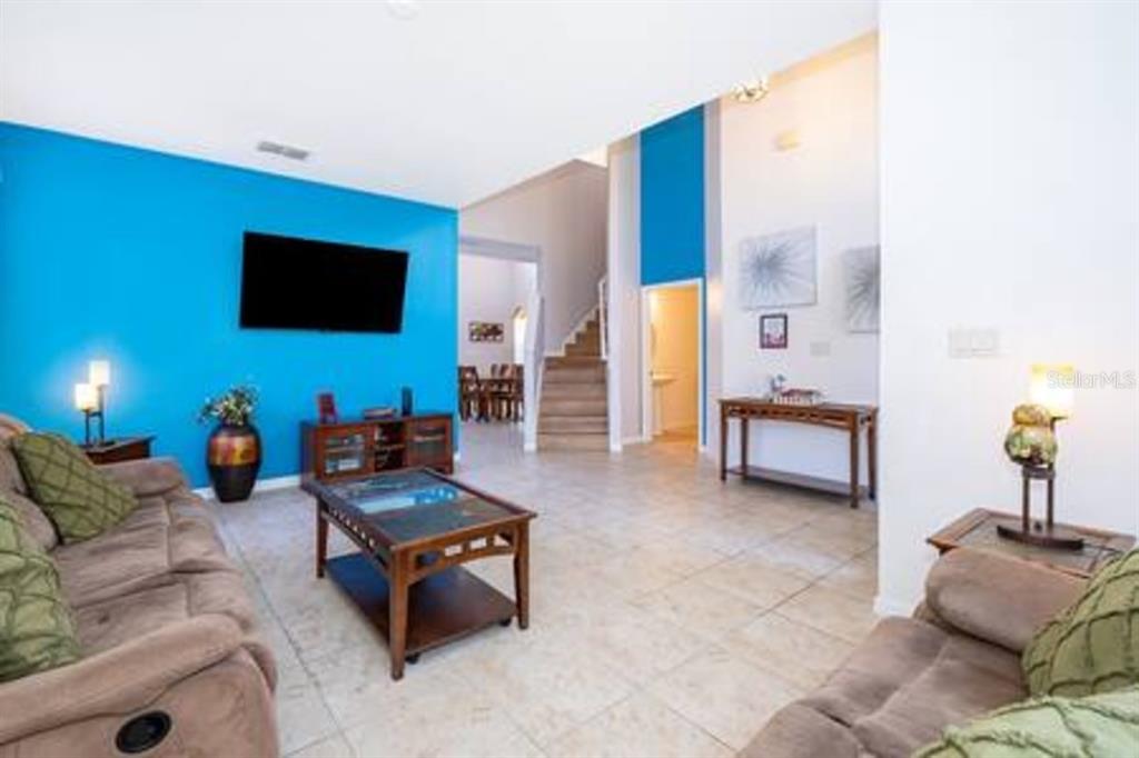 A living room features a bright blue accent wall, tile flooring, and a staircase — 4701 RUBY RED LANE, KISSIMMEE, FL