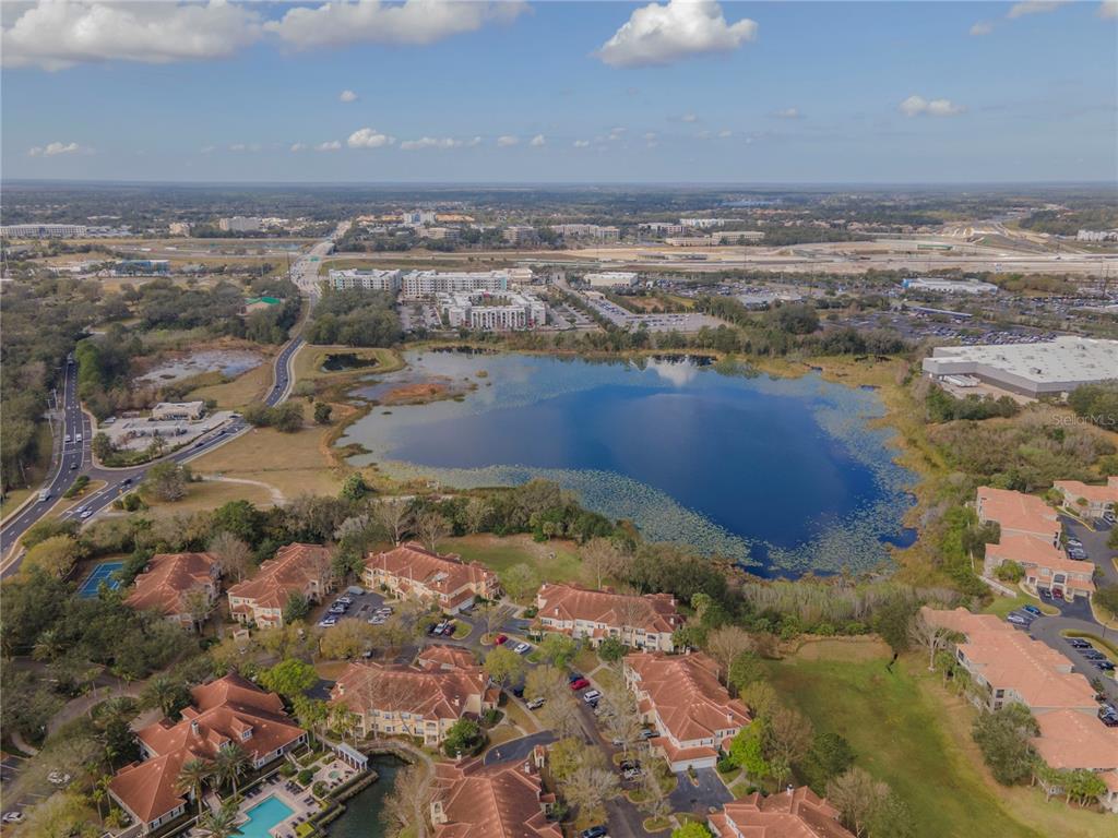 An aerial view shows a lake surrounded by residential buildings and a nearby highway — 4950 COUNTY ROAD 46A BOULEVARD, SANFORD, FL