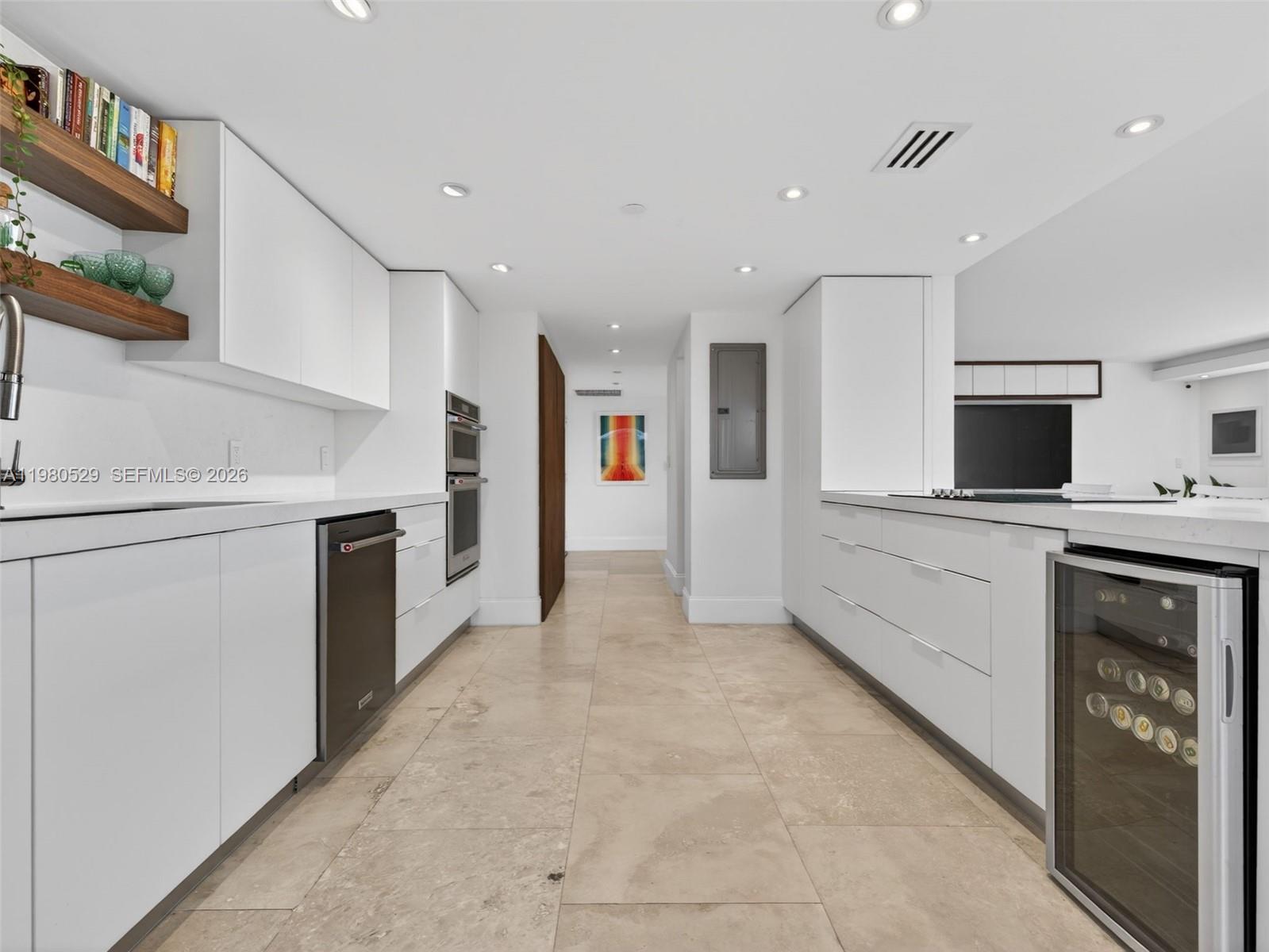 A modern galley kitchen features white flat-panel cabinetry, stainless steel appliances, and light tile flooring — 11113 Biscayne Blvd # 351, Miami FL 33181, MIAMI, FL