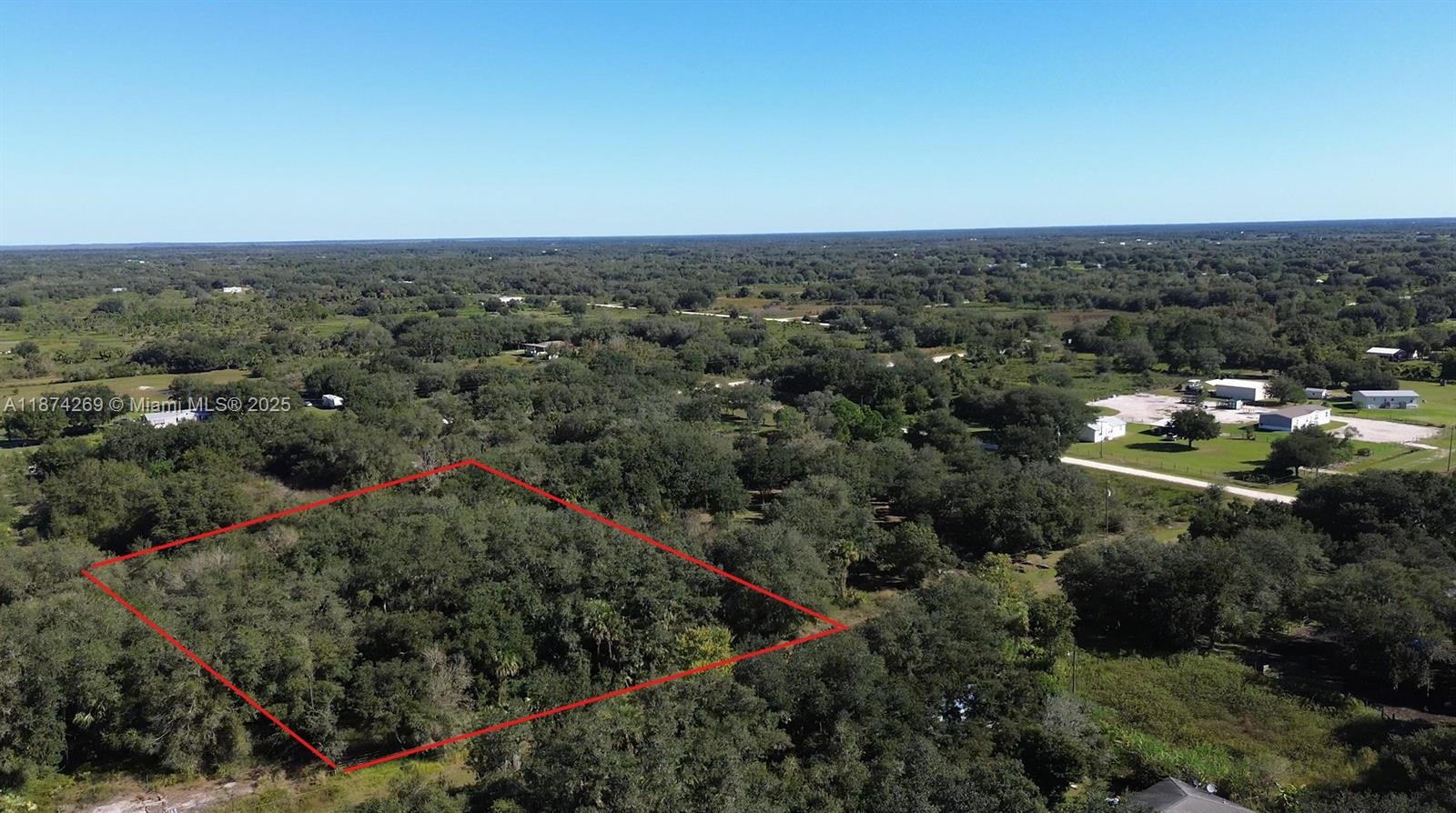 An aerial view shows a rectangular plot of land outlined in red amidst dense trees — 21229 NW 252 Street, Okeechobee FL 34972, OKEECHOBEE, FL
