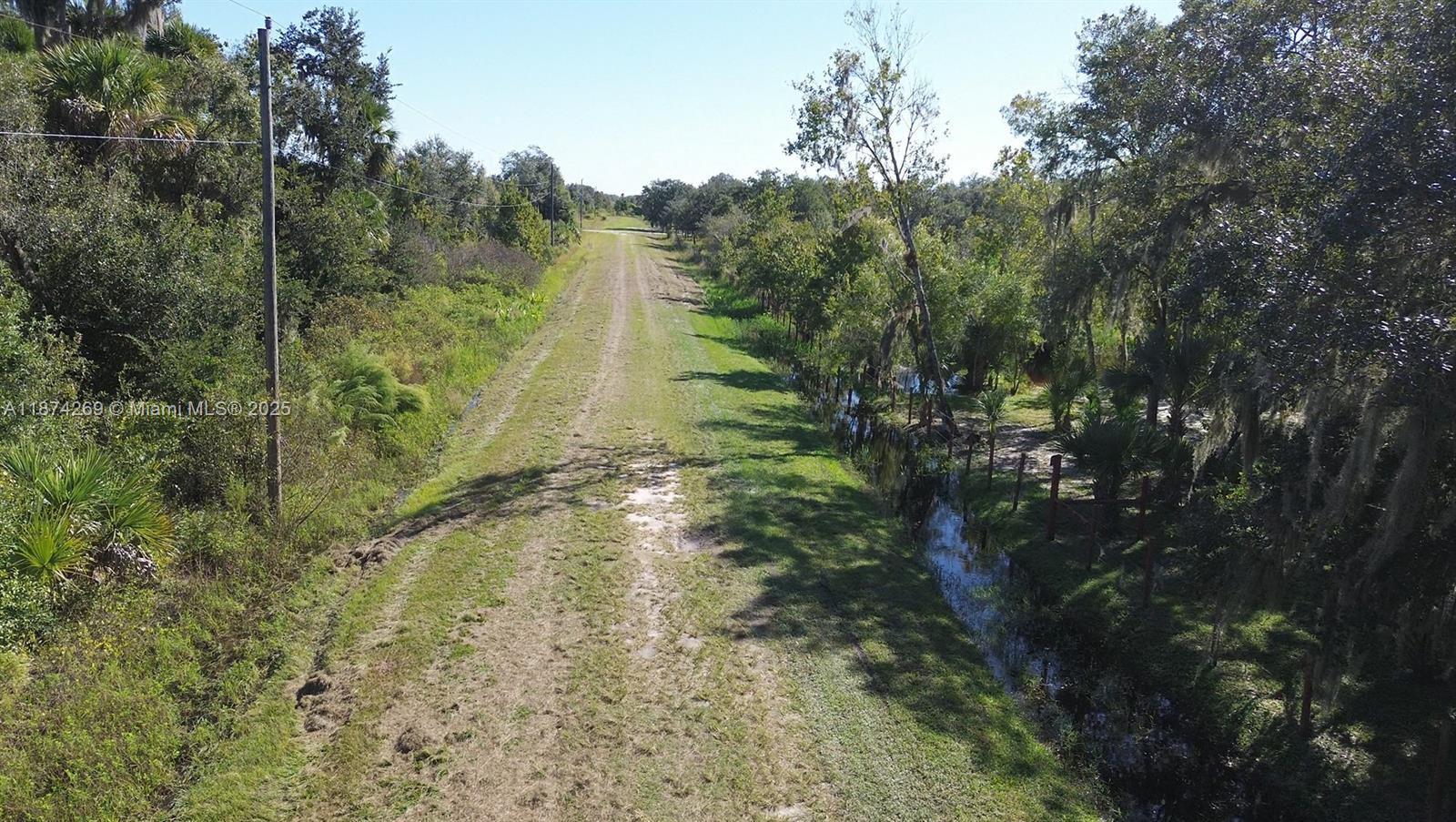 An aerial view shows a dirt path running between a drainage ditch and trees — 21229 NW 252 Street, Okeechobee FL 34972, OKEECHOBEE, FL