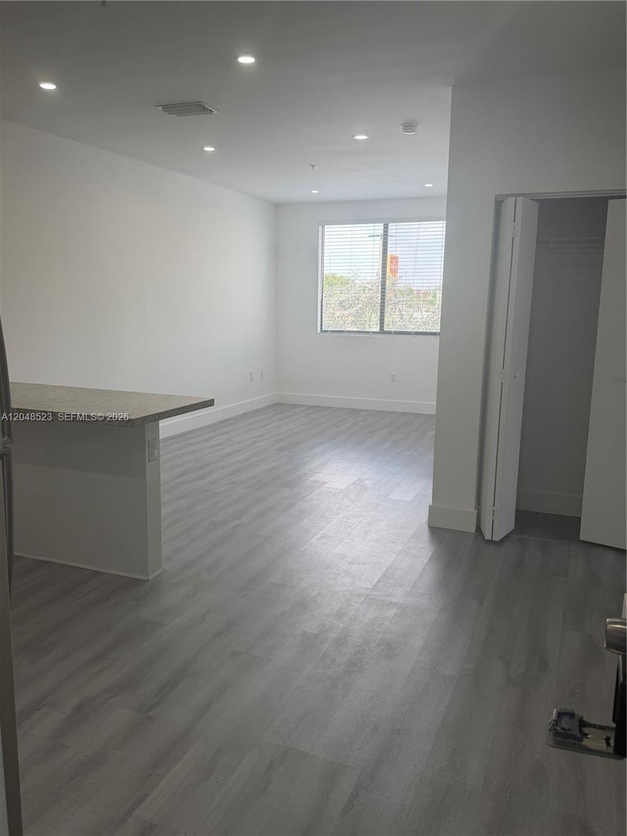 An open-concept room features light gray wood-look flooring, recessed lighting, and a kitchen peninsula — 853 E 24th St # 403, Hialeah FL 33013, HIALEAH, FL