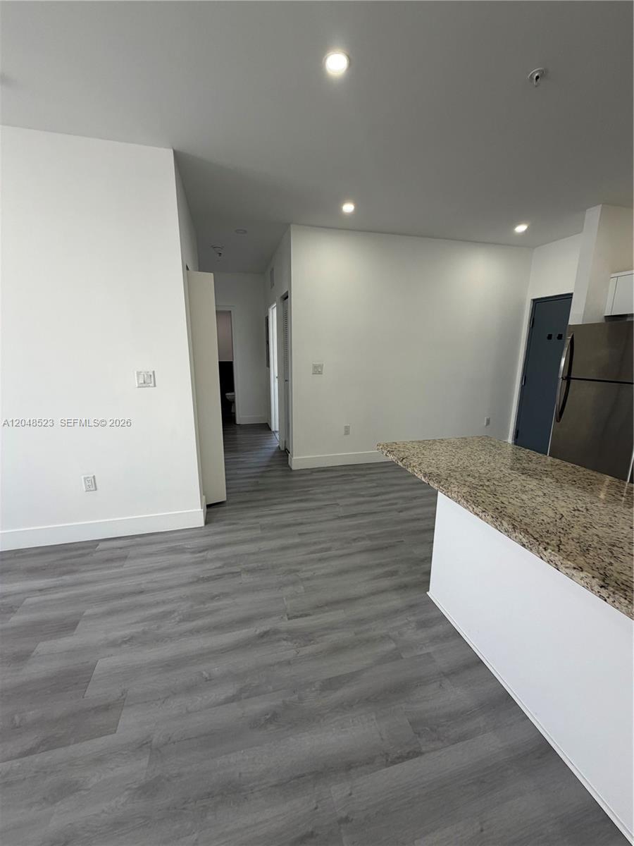 This interior view shows a kitchen area with granite countertops and gray wood-look flooring — 853 E 24th St # 403, Hialeah FL 33013, HIALEAH, FL