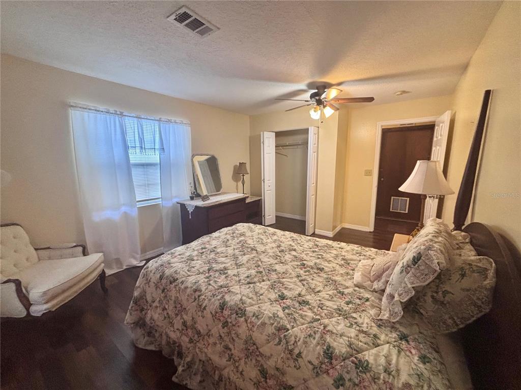A bedroom features a floral bedspread, a white armchair, a dresser, and a closet — 1513 N CENTRAL AVENUE, KISSIMMEE, FL