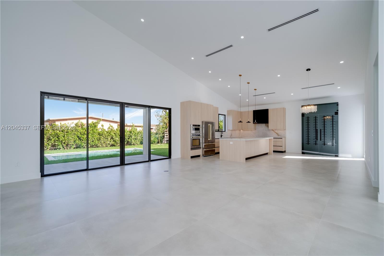 A bright, minimalist entryway features high ceilings, large windows, a modern chandelier, and light-colored tile — 4321 SW 99th Ave, Miami FL 33165, MIAMI, FL