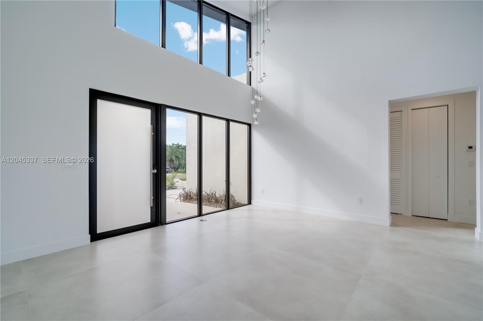 A modern open-concept kitchen and living area features light wood cabinetry and large glass doors — 4321 SW 99th Ave, Miami FL 33165, MIAMI, FL
