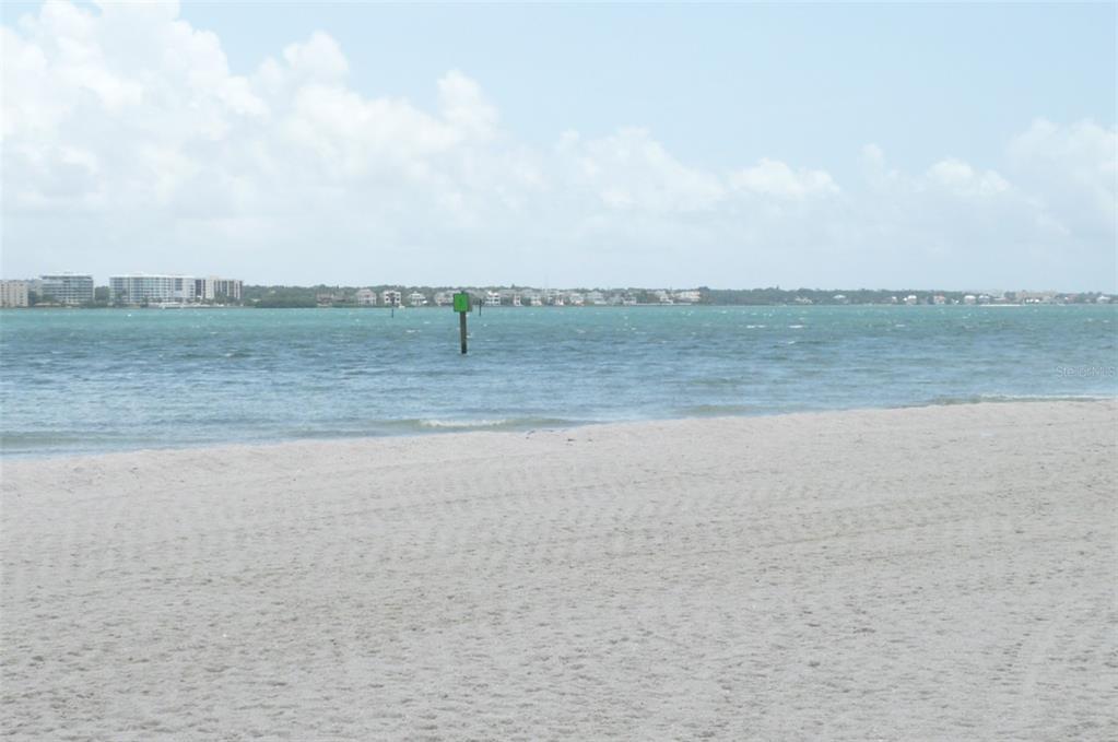 A sandy beach overlooks a body of water with a green navigation marker in the distance — 895 S GULFVIEW BOULEVARD UNIT 303, CLEARWATER BEACH, FL