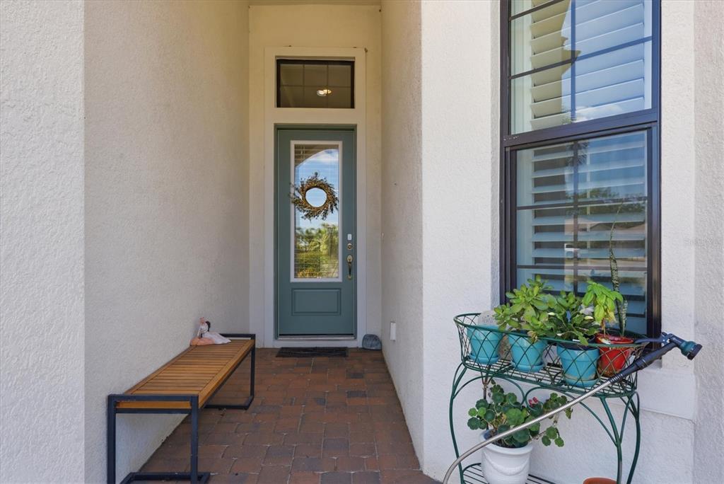 A front entryway features a teal door, a wooden bench, and a potted plant stand — 175 NOLEN DRIVE, VENICE, FL
