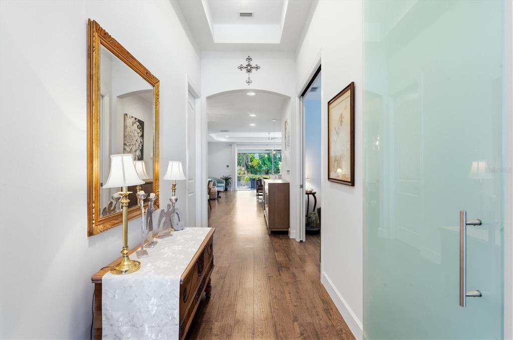 A hallway with wood flooring, a console table, a mirror, and a frosted glass door — 175 NOLEN DRIVE, VENICE, FL