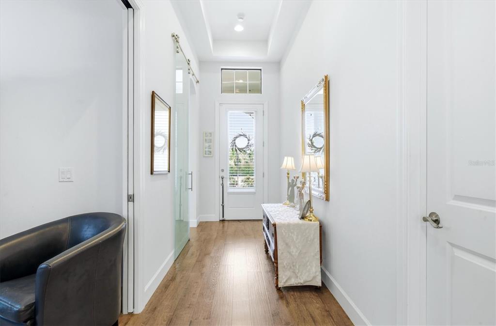 A bright entryway features wood-look flooring, a white door with a transom window, and mirrors — 175 NOLEN DRIVE, VENICE, FL