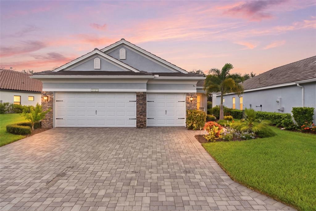 A single-story house with a three-car garage and a paved driveway at sunset — 3121 HERITAGE PINES DRIVE, FORT MYERS, FL