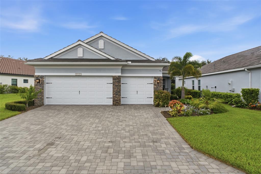 A single-story house with a paved driveway, two garage doors, and a stone-accented exterior — 3121 HERITAGE PINES DRIVE, FORT MYERS, FL