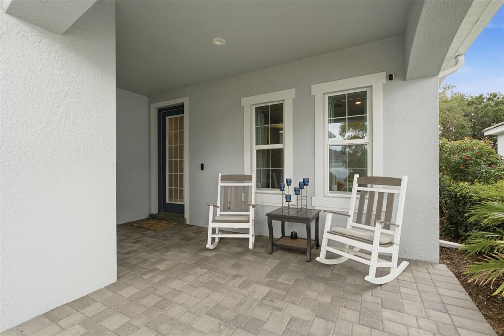 A covered front porch features gray pavers, two rocking chairs, and a small side table — 3121 HERITAGE PINES DRIVE, FORT MYERS, FL
