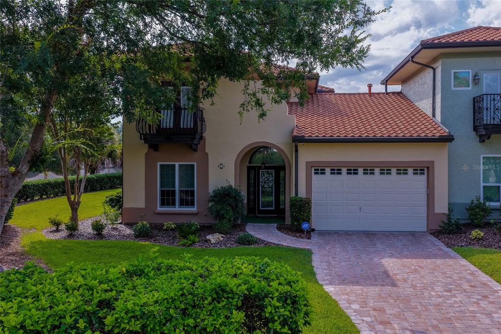 A two-story house with a tiled roof, a brick driveway, and a small balcony — 1259 AVENIDA DE LAS CASAS, LADY LAKE, FL