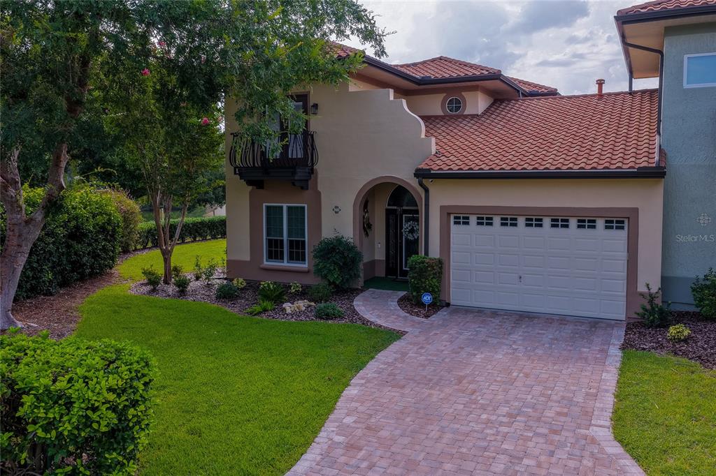 A two-story stucco house with a tile roof, a balcony, and a brick paver driveway — 1259 AVENIDA DE LAS CASAS, LADY LAKE, FL
