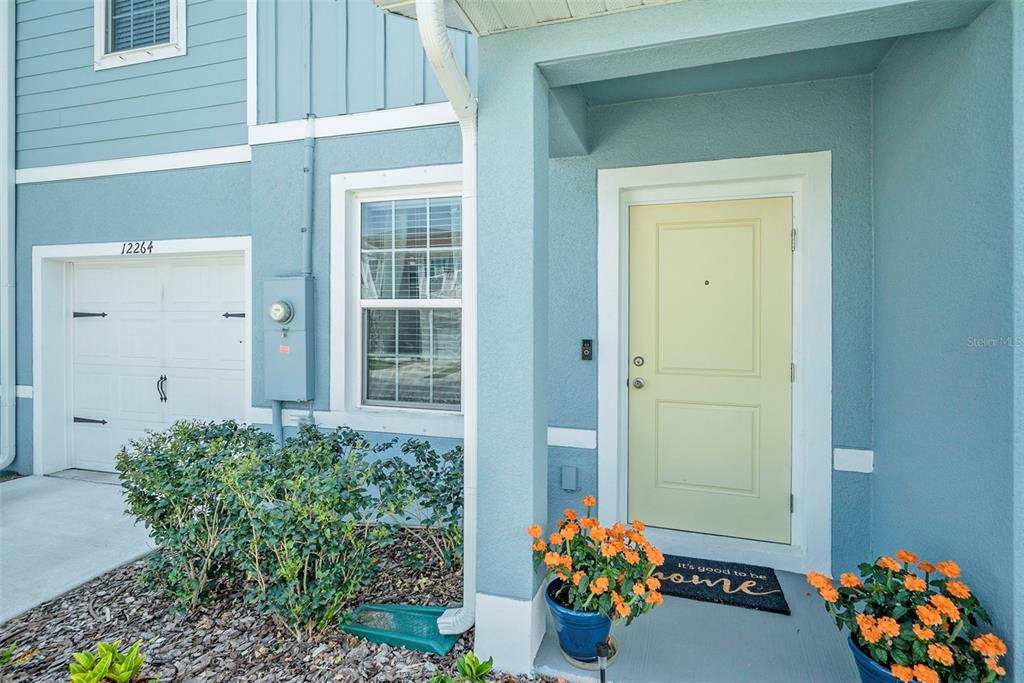 The exterior of a blue house features a light yellow front door and a garage — 12264 GRIZZLY LANE, NEW PORT RICHEY, FL