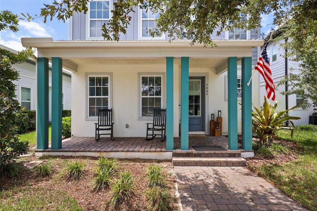A front porch with teal columns, two rocking chairs, and a brick walkway — 7805 NEMOURS PARKWAY, ORLANDO, FL