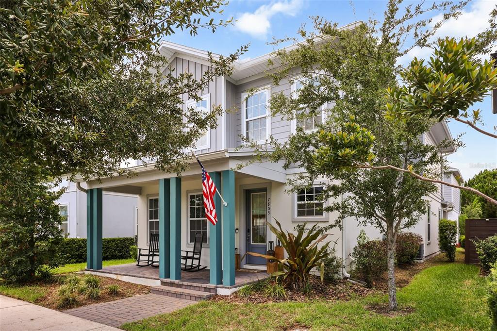 A two-story house with a front porch, teal columns, and a brick walkway — 7805 NEMOURS PARKWAY, ORLANDO, FL