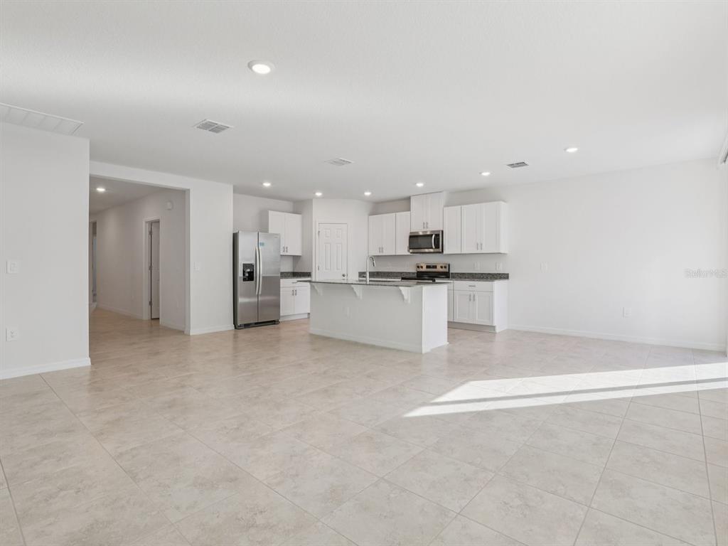 A bright, open-concept kitchen features white cabinetry, stainless steel appliances, and a central island — 2896 WILD OLIVE DRIVE, ST CLOUD, FL