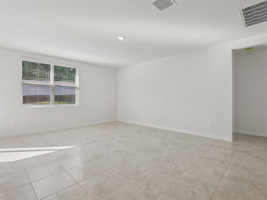 An empty room with white walls, light-colored tile flooring, and a single window with blinds — 2896 WILD OLIVE DRIVE, ST CLOUD, FL