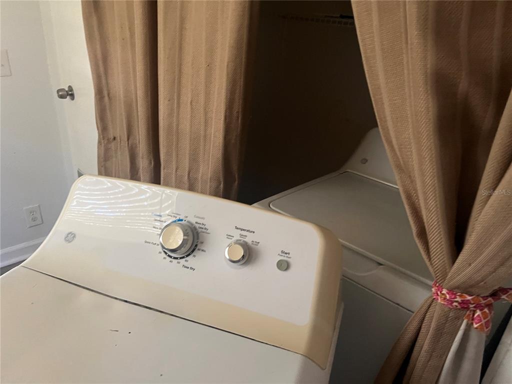 A laundry area features a GE dryer and a washing machine hidden behind brown curtains — 9102 6TH AVENUE, JACKSONVILLE, FL