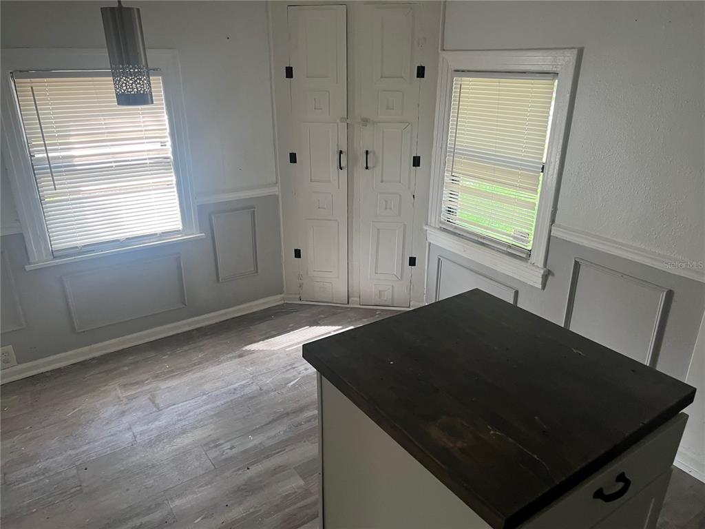 A room with gray wainscoting, wood-look flooring, two windows with blinds, and a central island — 9102 6TH AVENUE, JACKSONVILLE, FL