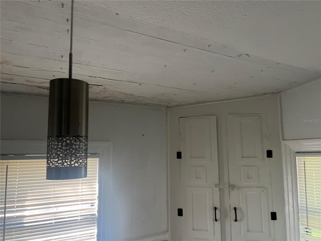 A room features a pendant light, white paneled walls, and a wooden plank ceiling — 9102 6TH AVENUE, JACKSONVILLE, FL