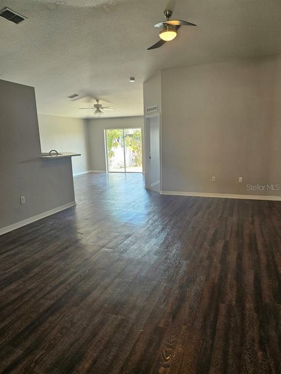 An open-concept living area features dark wood-look flooring, light gray walls, and two ceiling fans — 10917 BANYAN WOOD WAY, RIVERVIEW, FL