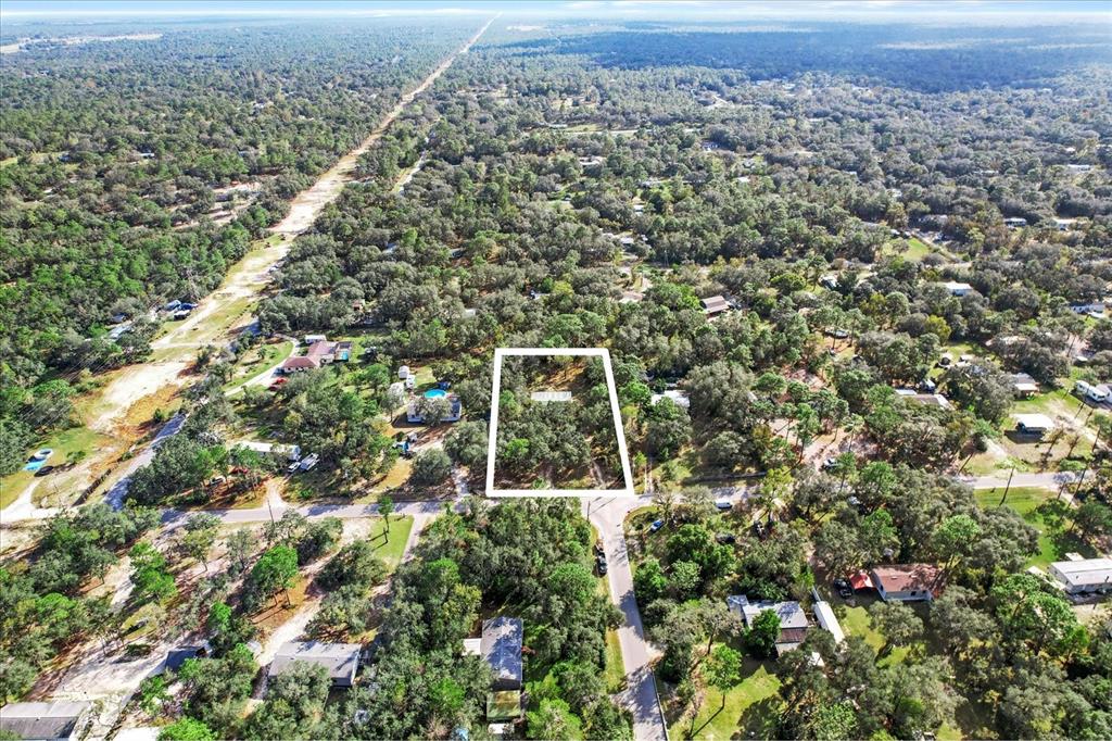 An aerial view shows a rectangular vacant lot outlined in white within a wooded area — 5114 W ROCHELLE STREET, HOMOSASSA, FL