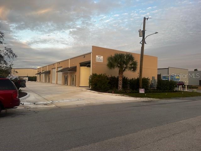 A tan commercial warehouse building with multiple bay doors and a palm tree in front — 18803 TITUS, HUDSON, FL