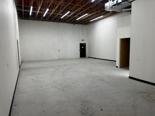 An empty industrial warehouse space features a concrete floor, white walls, and exposed ceiling rafters — 18803 TITUS, HUDSON, FL