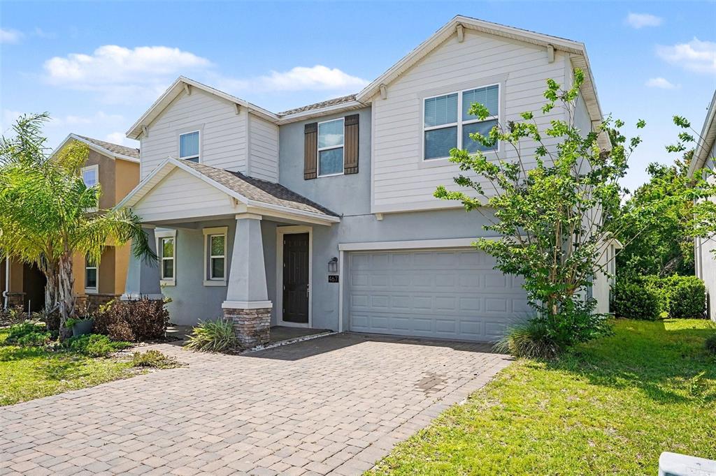 A two-story house with light siding, a stone-based pillar, and a paved driveway — 467 BRUNSWICK DRIVE, DAVENPORT, FL