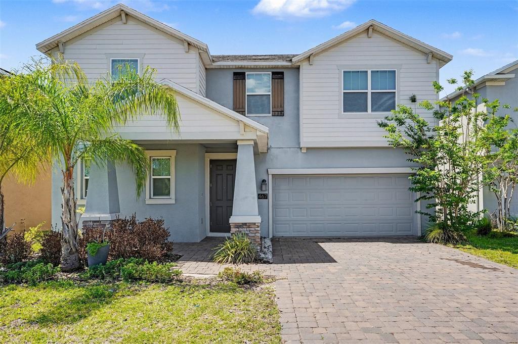 A two-story house with a gray stucco exterior, a paved driveway, and a palm tree — 467 BRUNSWICK DRIVE, DAVENPORT, FL