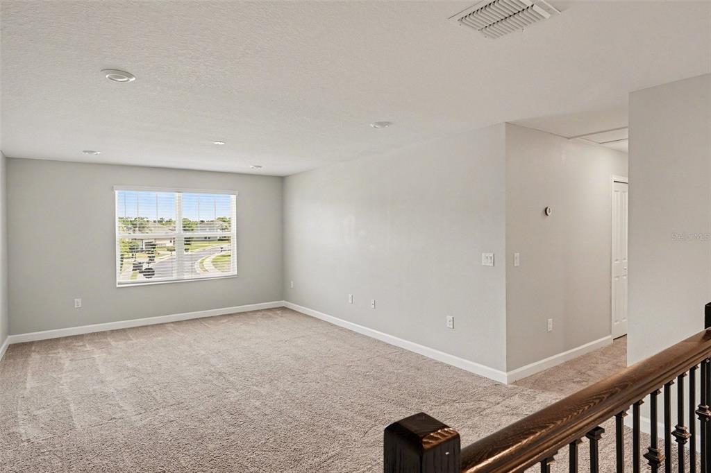 A carpeted loft area features light gray walls, recessed lighting, and a window overlooking a neighborhood — 467 BRUNSWICK DRIVE, DAVENPORT, FL
