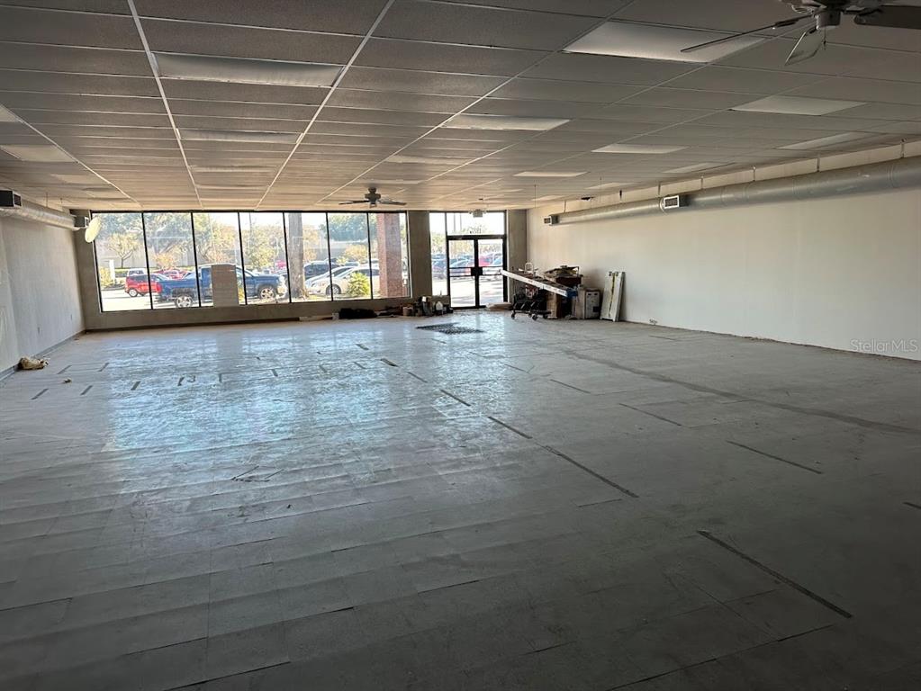 An empty commercial space features a drop ceiling, large windows, and exposed concrete flooring — 1927 SW COLLEGE ROAD UNIT C, OCALA, FL