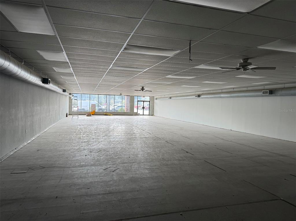 An empty commercial space features a drop ceiling, exposed ductwork, and large front windows — 1927 SW COLLEGE ROAD UNIT C, OCALA, FL