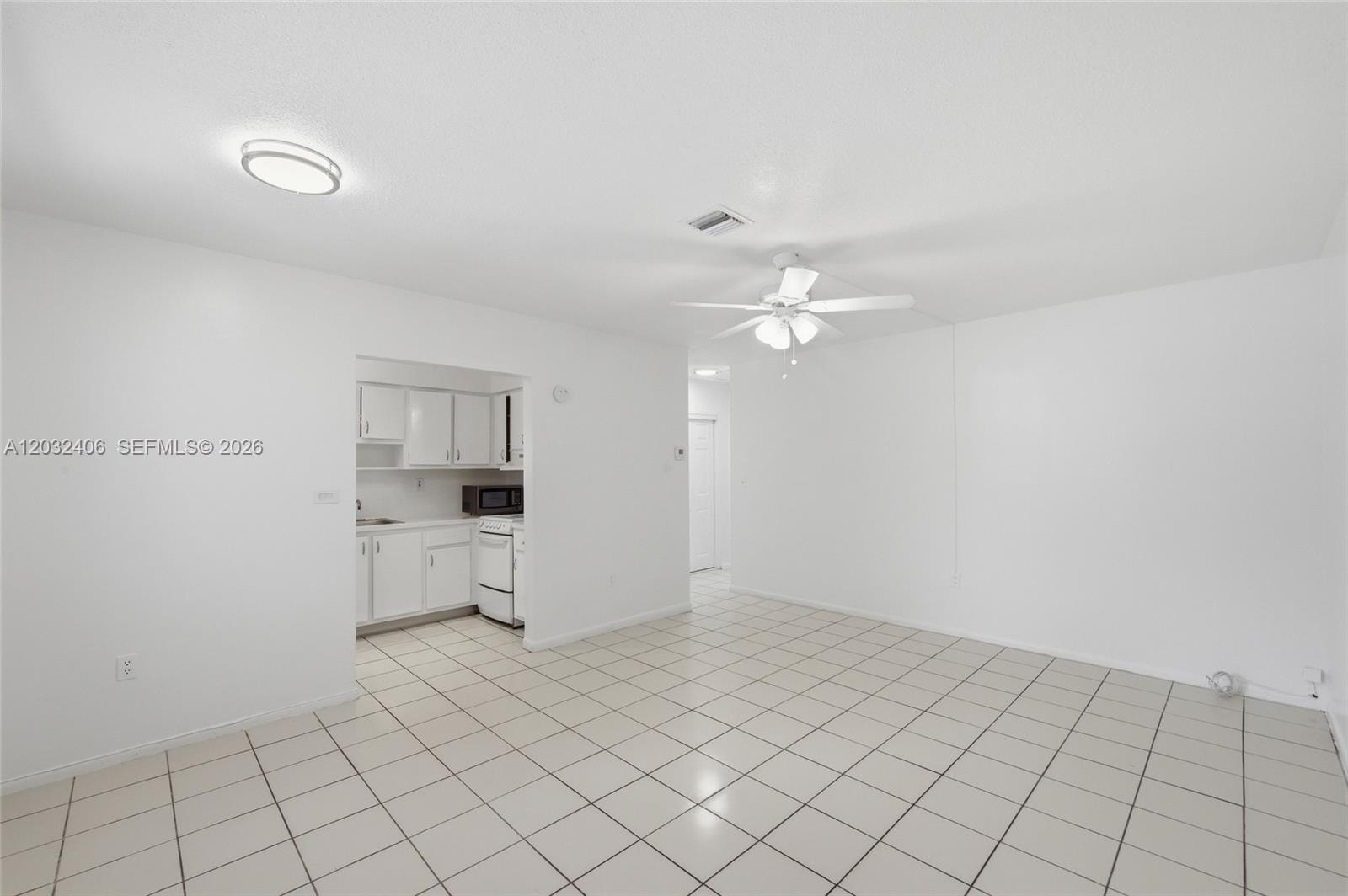 A white-walled room features tiled flooring, a ceiling fan, and an adjacent small kitchen — MIRAMAR, FL