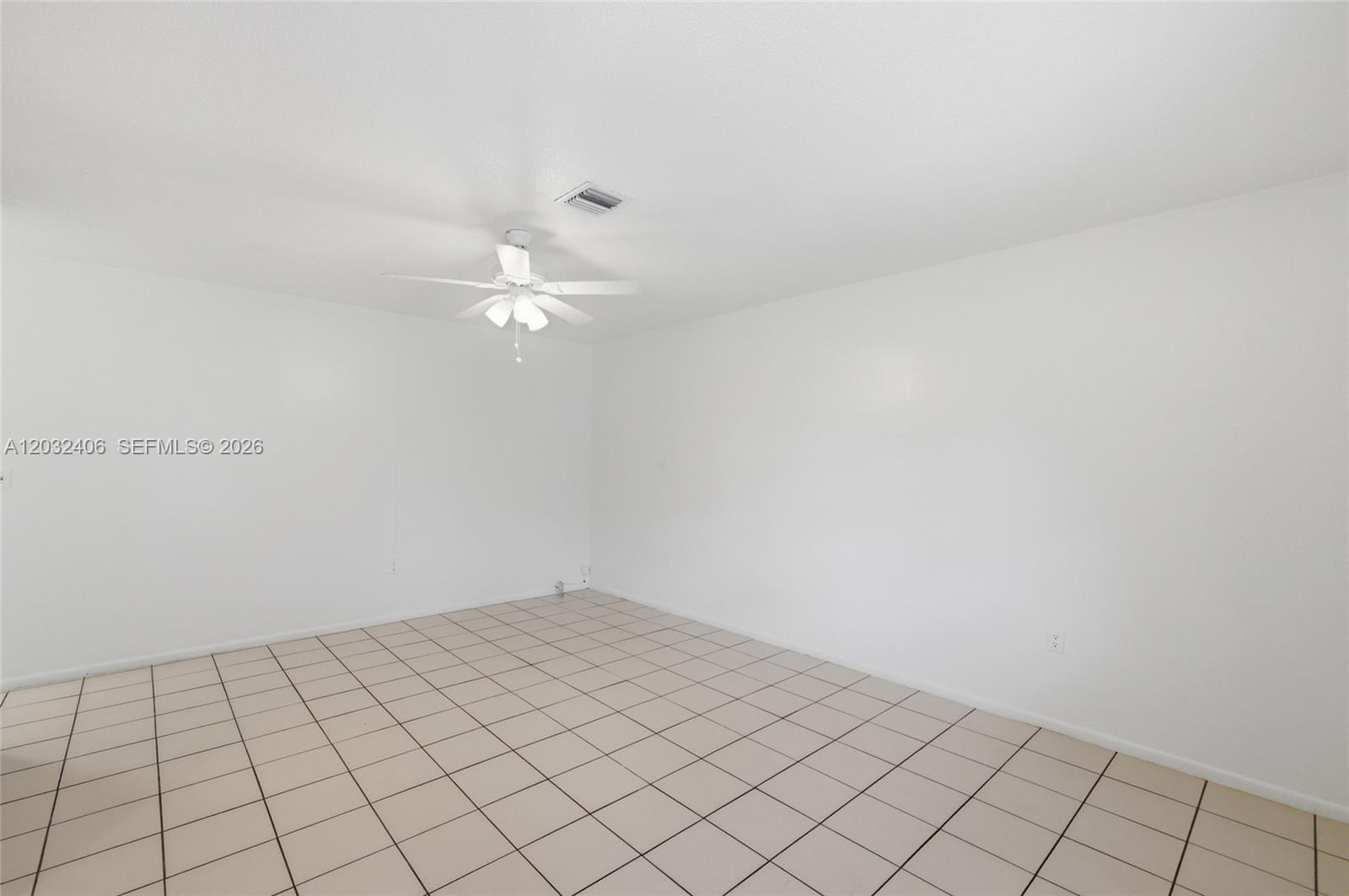 An empty room features white walls, a ceiling fan, and light-colored square floor tiles — MIRAMAR, FL