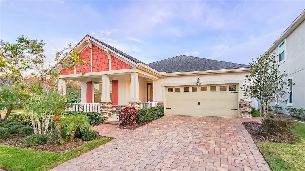 A single-story house features a red shingled gable, stone accents, and a paved driveway — 8201 CORKFIELD AVENUE, ORLANDO, FL