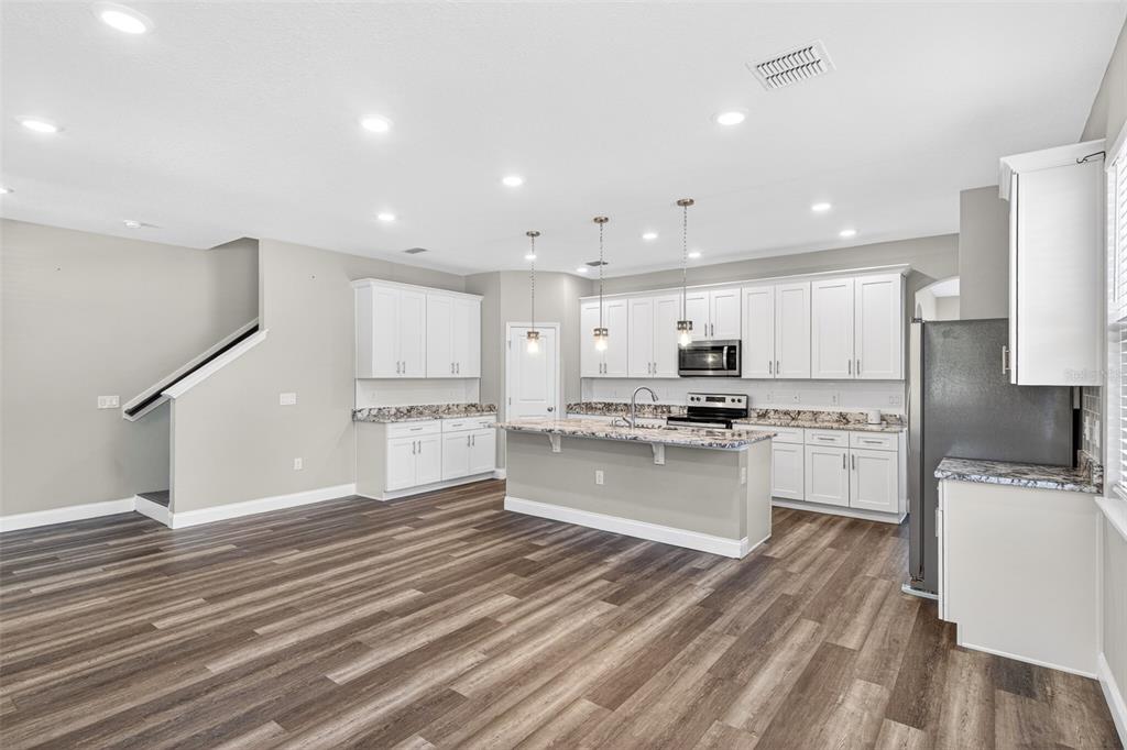 A kitchen with white cabinets, granite countertops, an island, and wood-look flooring — 801 PECAN AVENUE, SANFORD, FL
