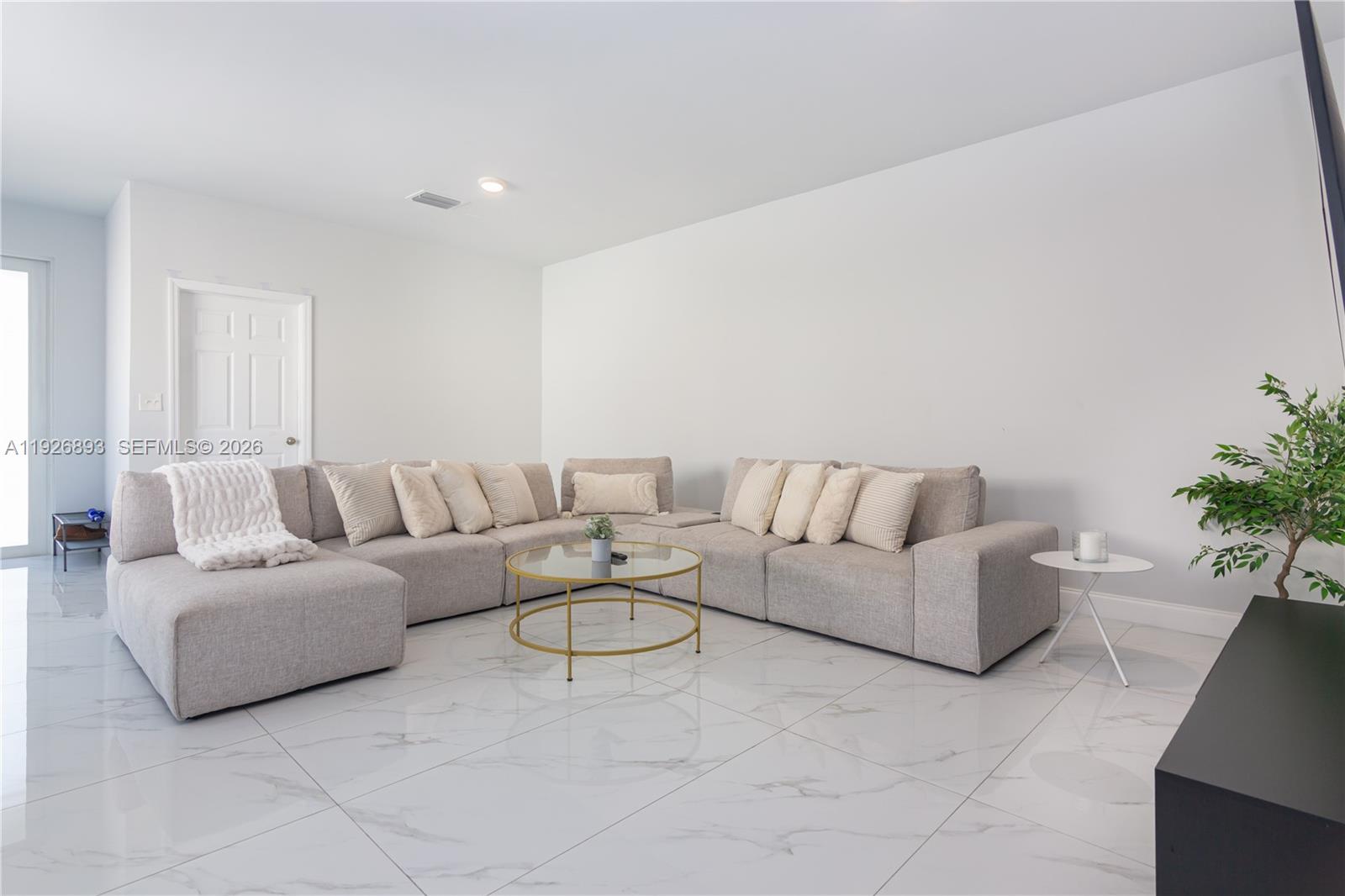 A living room features a large sectional sofa, a glass coffee table, and marble flooring — 1968 NW 25th Ave, Miami FL 33125, MIAMI, FL